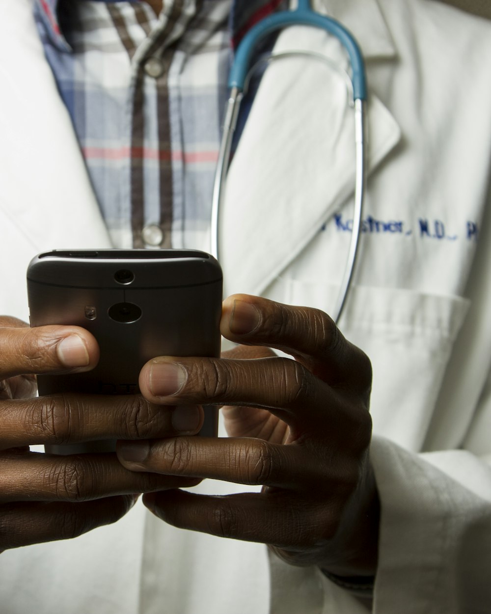 A doctor in a white coat holding a smartphone